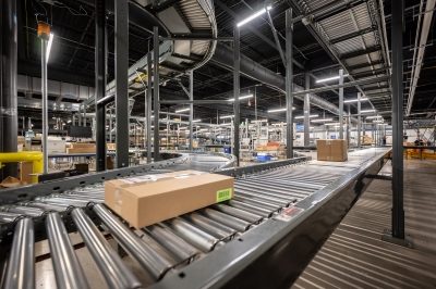 A box travels on a conveyor belt through a large warehouse.