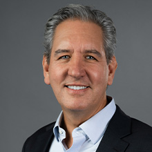 Headshot of David Habiger in blue coat and smiling face.