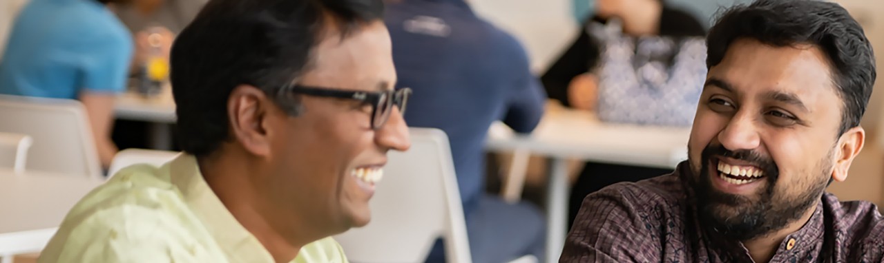 Three racially diverse employees laugh together while walking down a hallway.