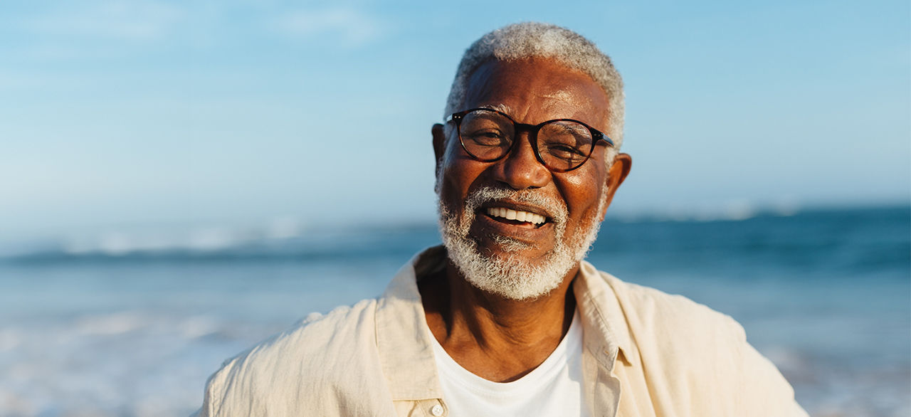 Smiling gray-haired man looks into camera on beach